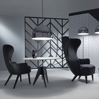 Black chairs with sleek contours and a contrasting white table, set against a geometric black-and-white background.