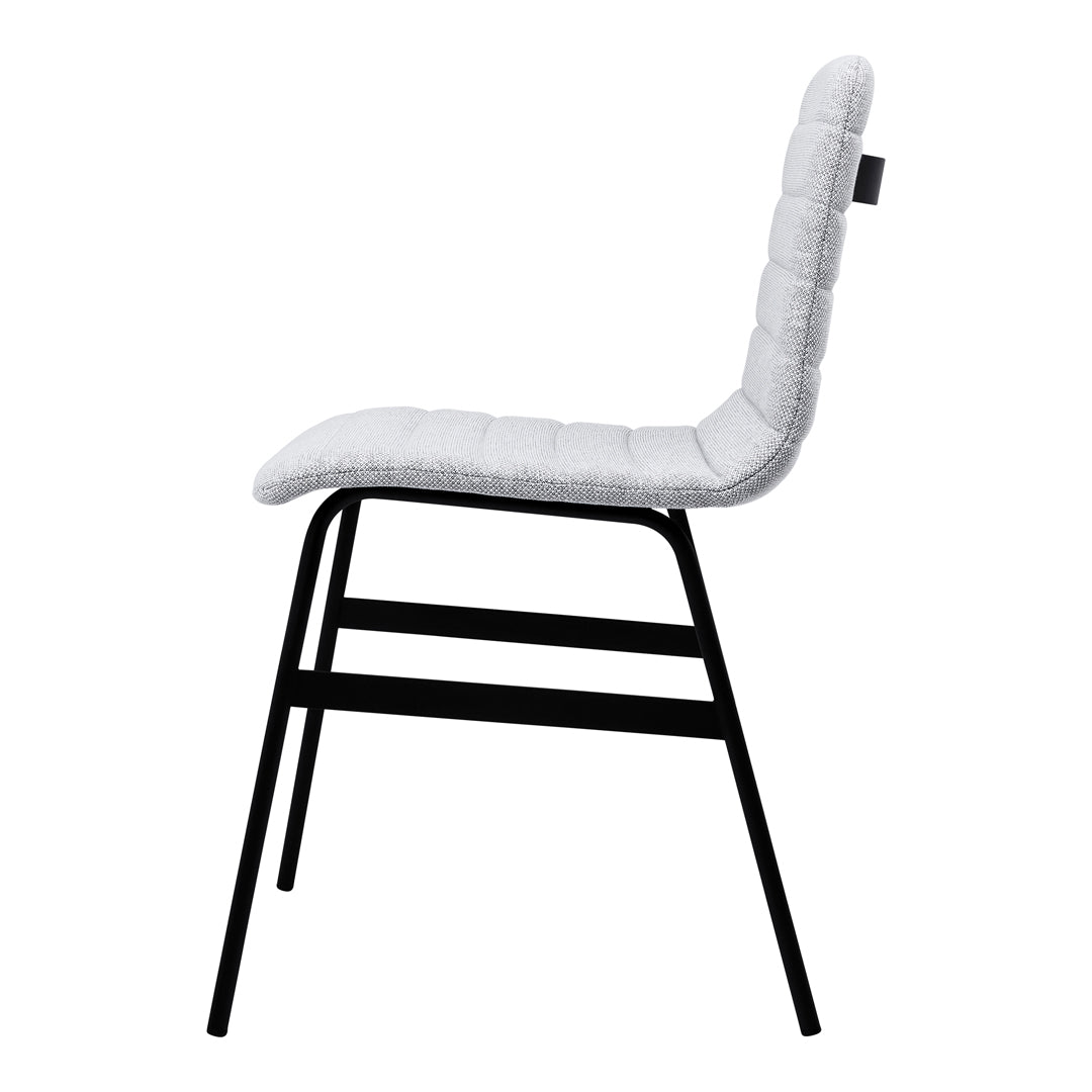 White upholstered chair with quilted texture and a sleek black metal frame, showcasing a modern minimalist style.