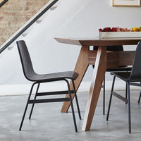 "Black minimalist chair with a smooth finish, paired with a natural wood dining table in a modern setting."