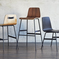 Three stylish wooden chairs: natural light wood, rich dark wood, and sleek black, all featuring contemporary designs.