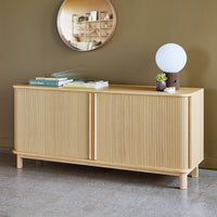 Light wood sideboard with vertical ribbed pattern, set against a muted olive green wall. Minimalist modern decor.