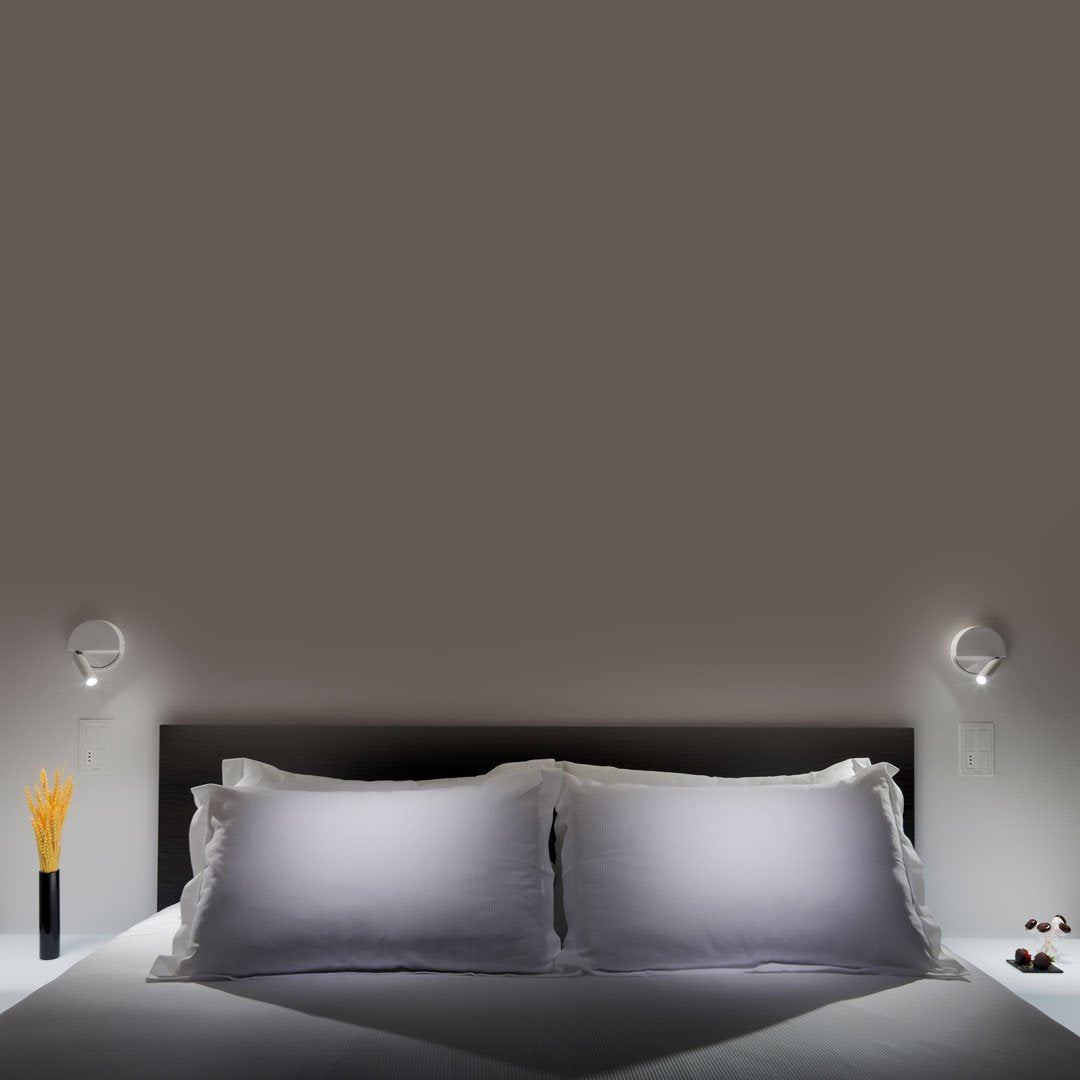 Gray wall backdrop with white bedding, featuring smooth textures and modern lamp designs.