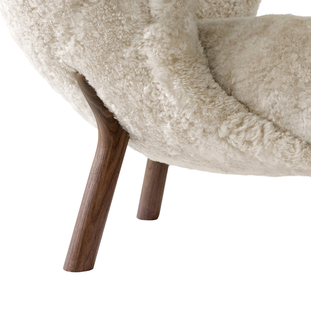 Cream plush chair with a textured surface and wooden legs in a rich walnut finish.
