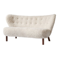 Cream-colored tufted sofa with a curved shape and plush faux sheepskin texture. Warm wooden legs enhance its modern aesthetic.
