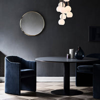 Elegant dark blue armchairs and a round black table against a sophisticated dark gray wall, featuring soft white pendant lights.