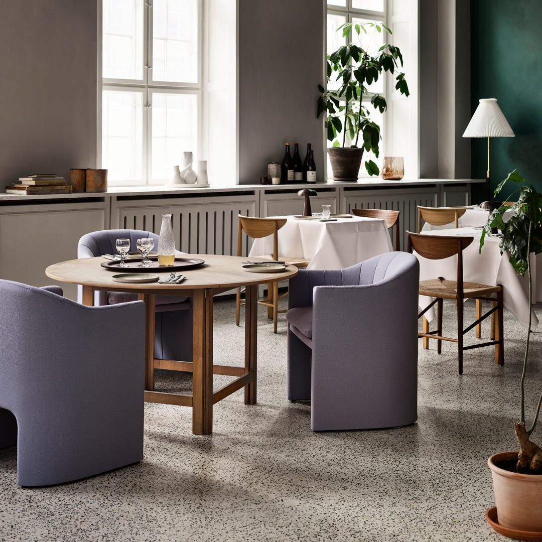 Modern dining room featuring soft lavender chairs, a round wooden table, and neutral-colored decor elements.