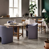 Modern dining room featuring soft lavender chairs, a round wooden table, and neutral-colored decor elements.