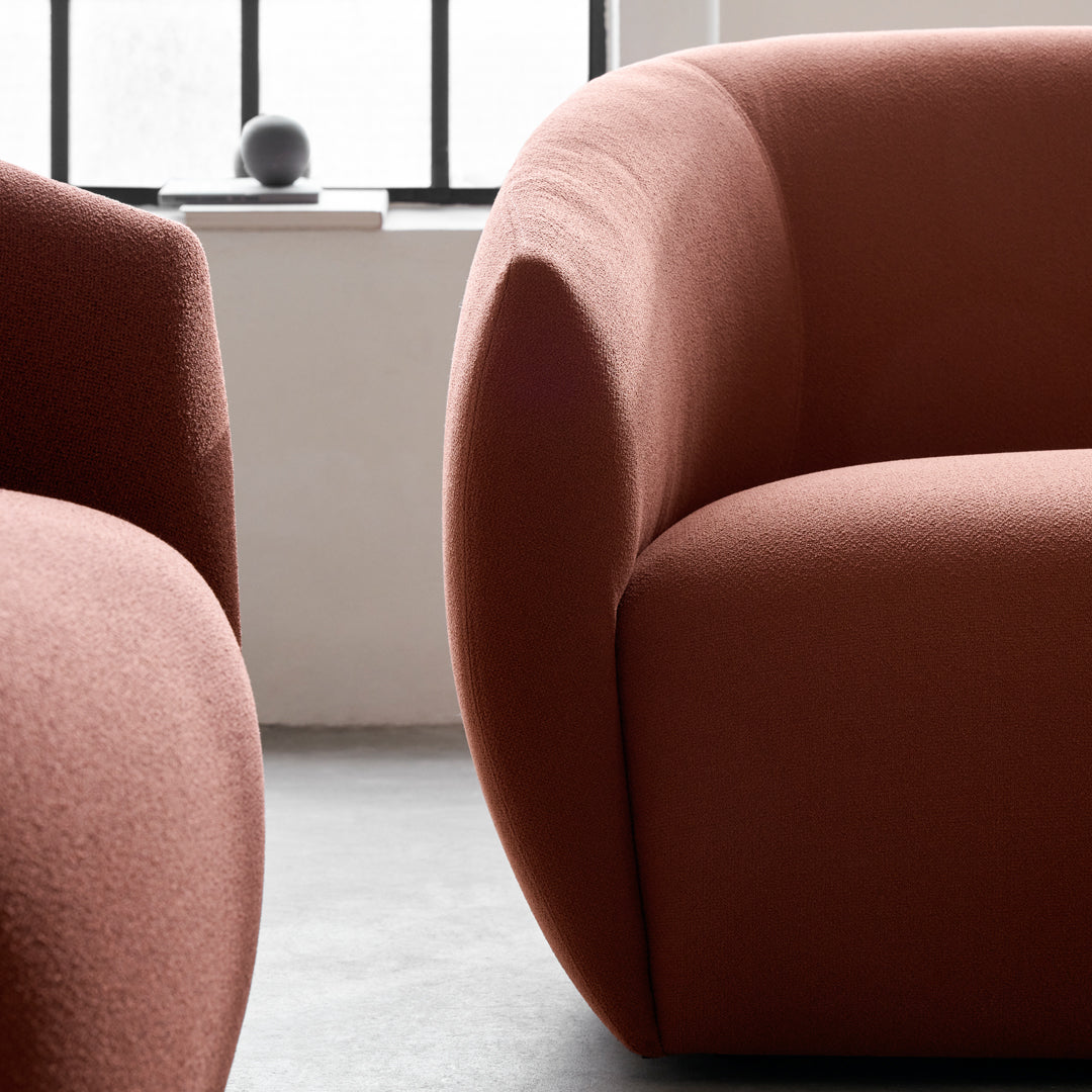 Terra-cotta curved sofa design featuring soft, textured fabric in a minimalist setting with a neutral background.