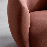 Textured, soft pink upholstery with a cozy, rounded design, enhancing modern interior aesthetics.