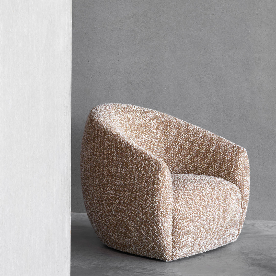 Textured beige armchair with a rounded silhouette, set against a minimalist gray background.