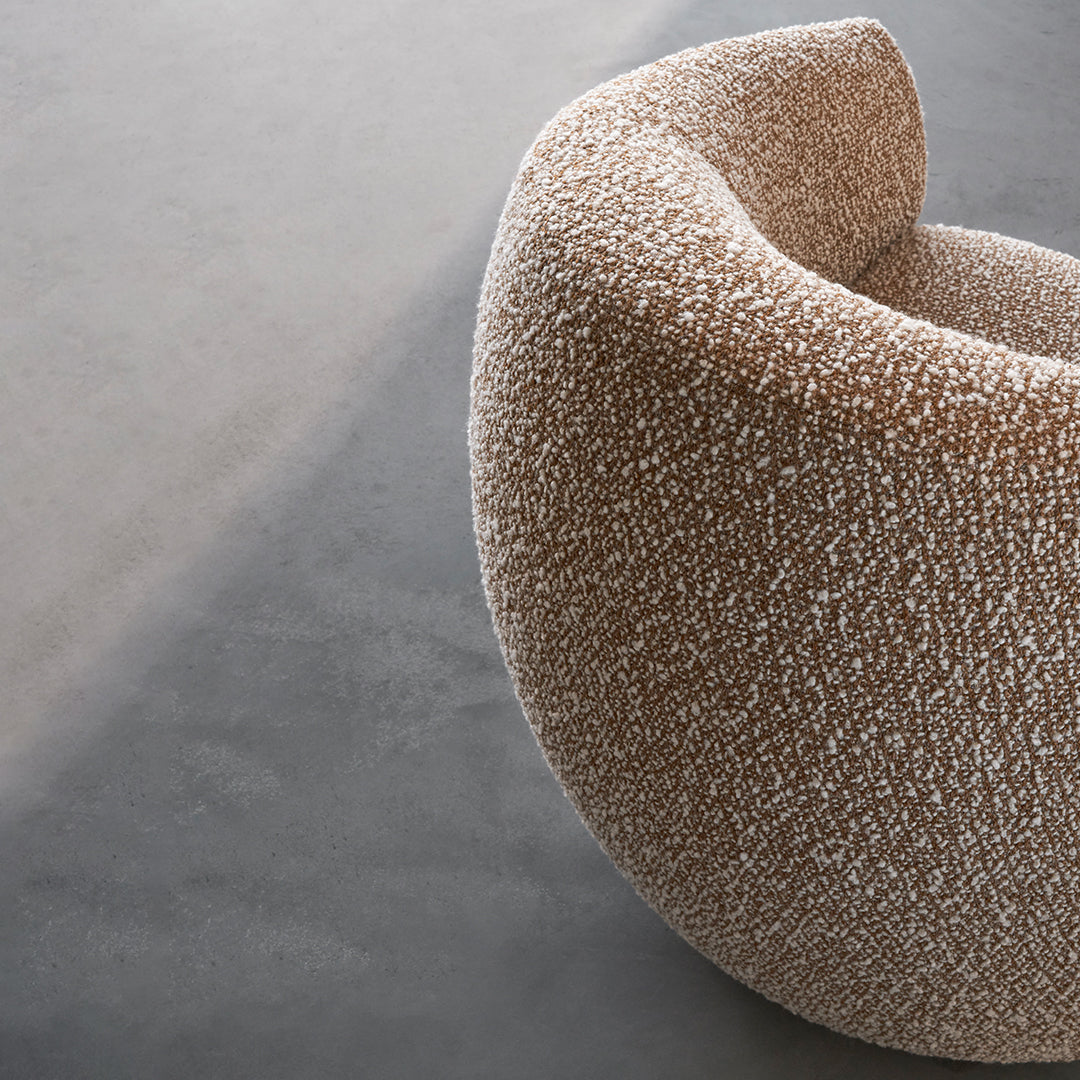 Textured brown chair with soft, rounded edges and light speckled pattern, set against a smooth gray background.