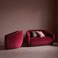 Velvet burgundy sofa and chair with bold, smooth curves, accented by soft pillows in muted tones.