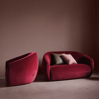 Velvet burgundy sofa and chair set with soft pink and dark green accent pillows against a muted brown backdrop.