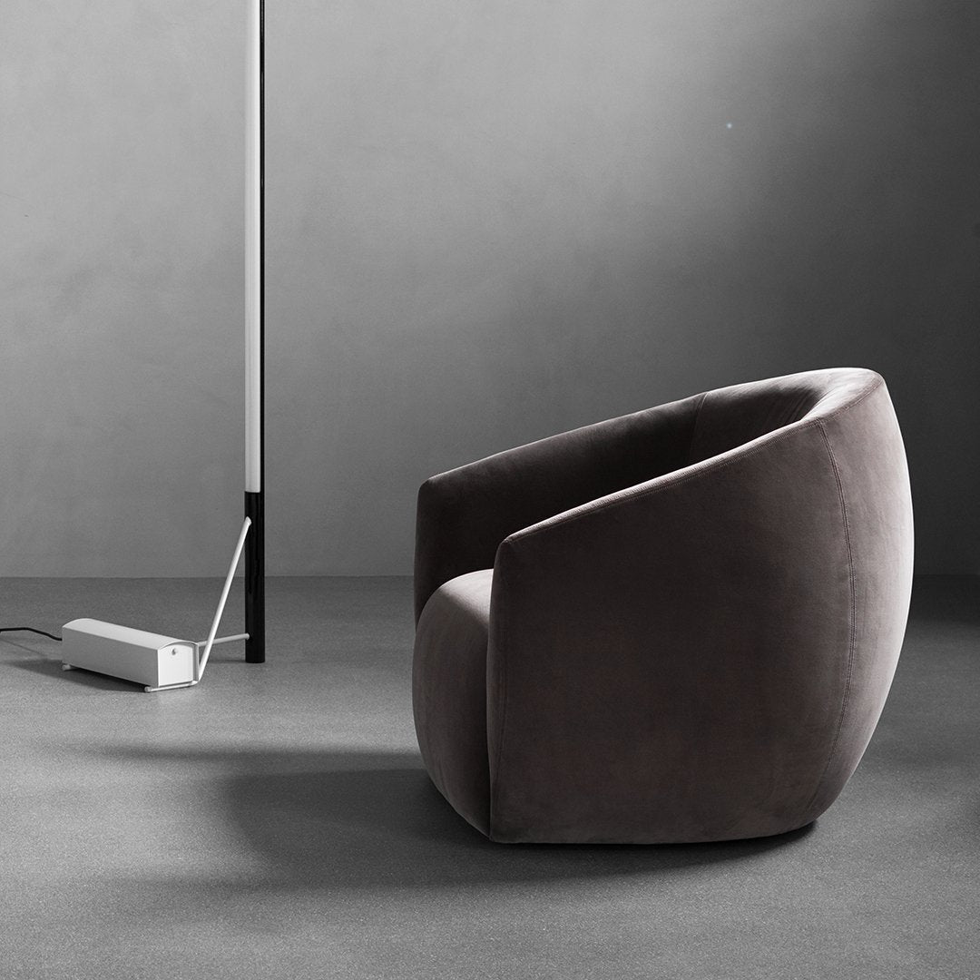 Plush, dark gray velvet accent chair with smooth, curved silhouette and minimalist design against a neutral backdrop.