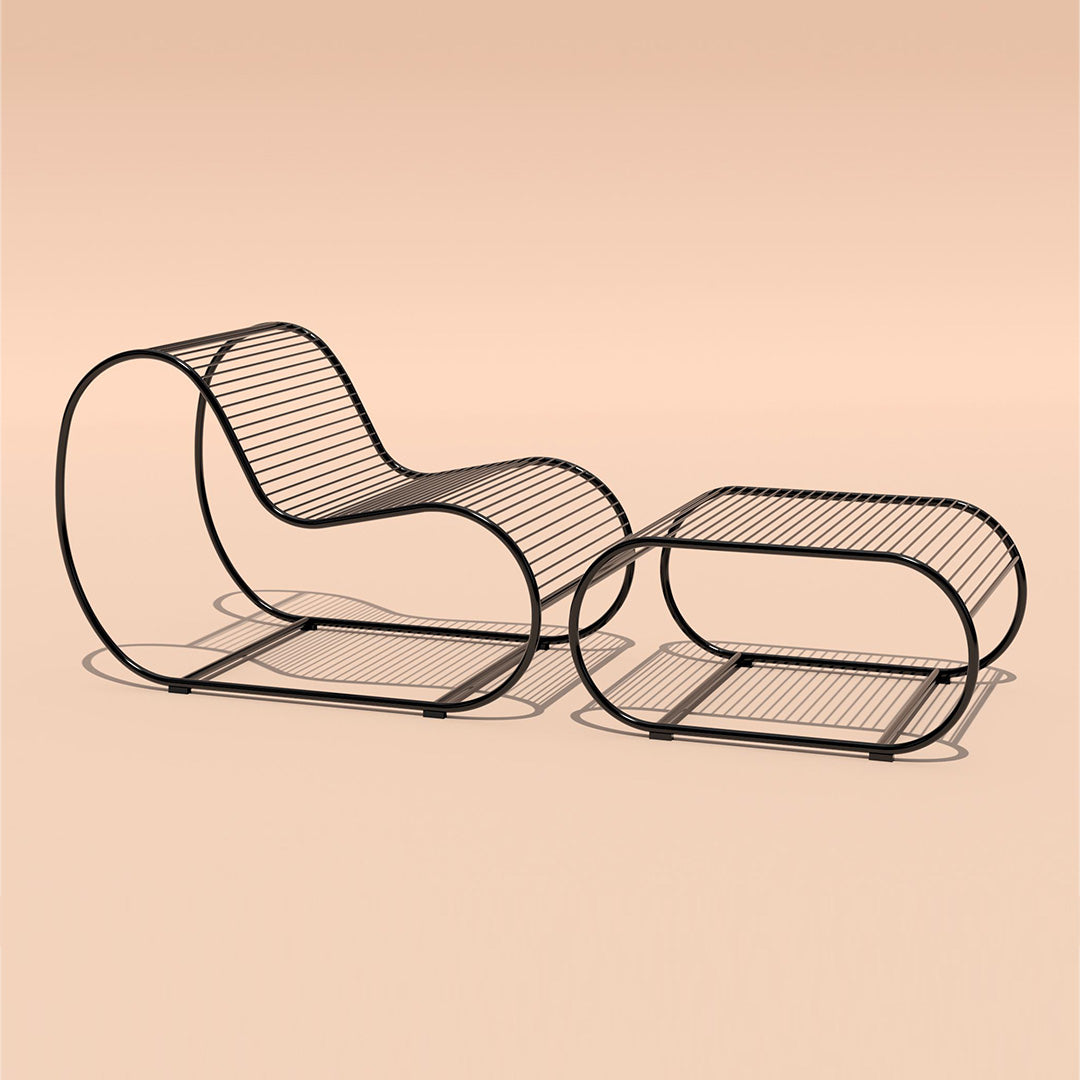 Black wire lounge chair and matching table on a soft peach background, showcasing a modern, minimalist design.