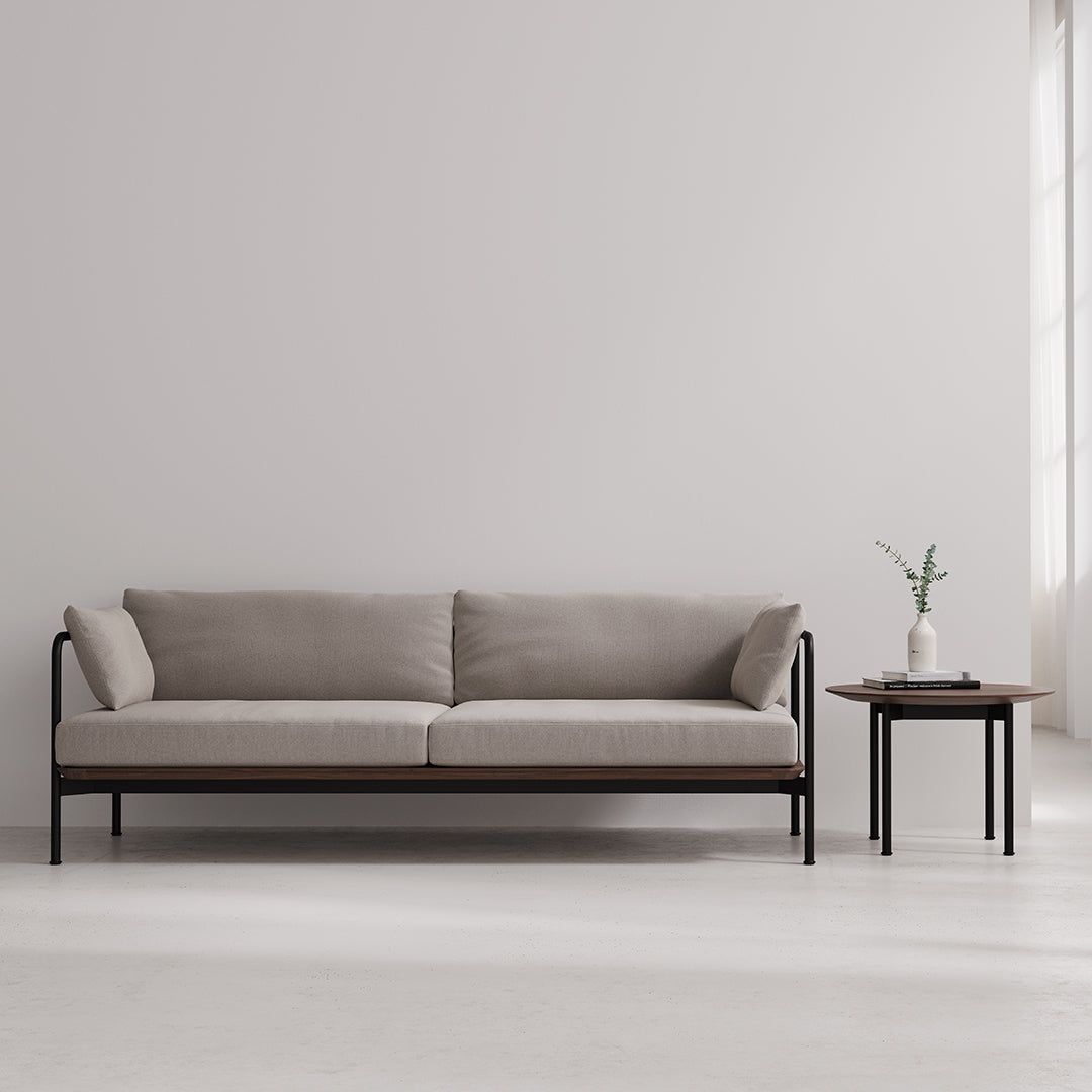 Neutral beige sofa with soft cushions and sleek black metal frame, paired with a minimalist wooden side table.