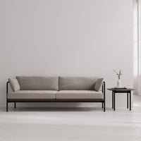 Neutral beige sofa with soft cushions and sleek black metal frame, paired with a minimalist wooden side table.