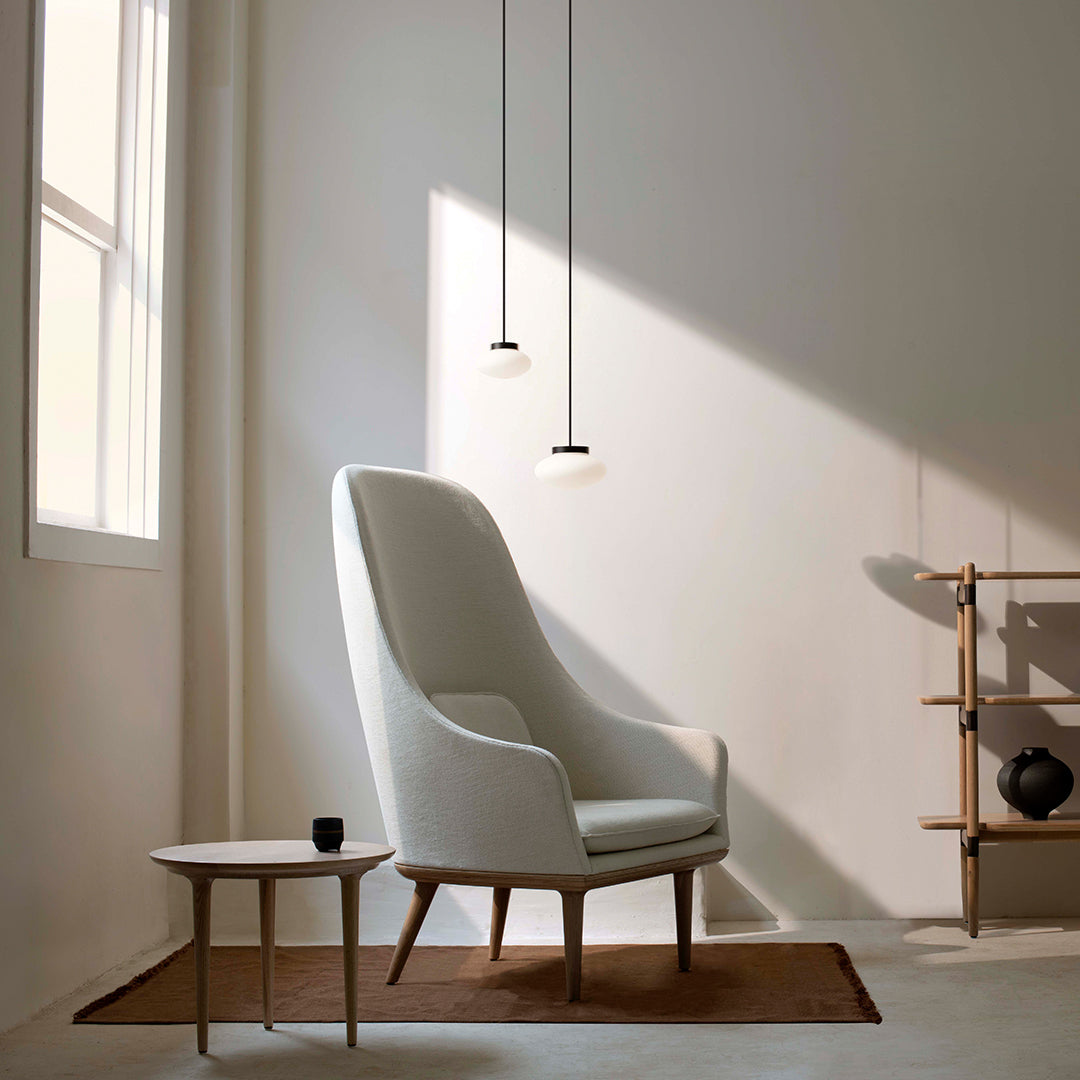 White upholstered armchair with wood legs, minimalistic design, set against a neutral-toned background.