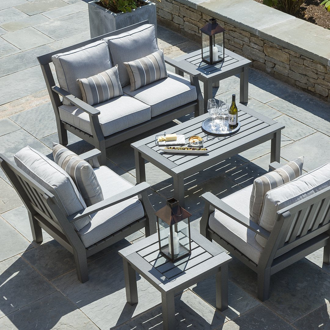 Gray outdoor furniture set with striped cushions, featuring a modern design on a stone patio. Perfect for elegant patios.