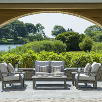 "Light gray outdoor furniture set with subtle striped cushions against a lush green landscape."