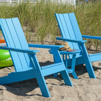 "Blue adirondack chairs on sandy beach, featuring a clean, modern design with slatted backs and matching table."