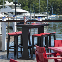 Black outdoor bar with red accents, surrounded by red chairs, set against a lake and marina backdrop.