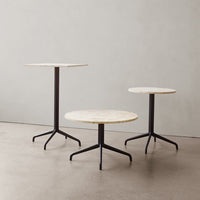 Set of three modern tables featuring round white marble tops and sleek black metal legs. Elegant and contemporary design.
