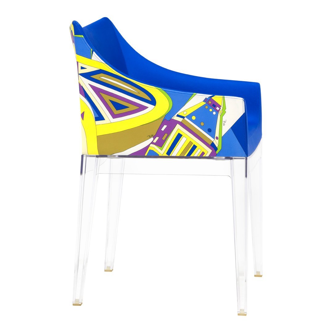 Colorful blue chair featuring vibrant geometric patterns in yellow, purple, and green tones against a clear base.