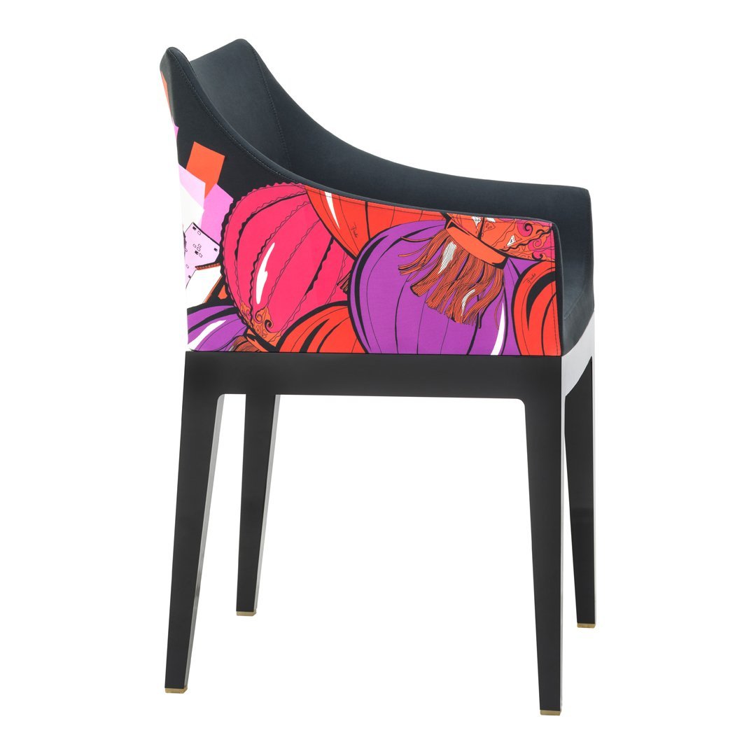 Colorful chair with vibrant floral patterns in purple, pink, and orange, contrasted by a sleek black frame.