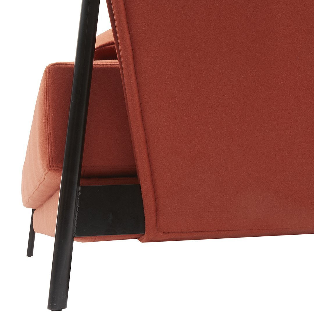 Rust-orange upholstered chair with a sleek black metal frame, showcasing a minimalist design and clean lines.