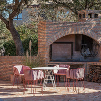 "Elegant patio set with pink chairs and a sleek white table, set against a rustic brick backdrop."