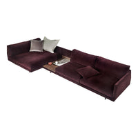 Plush burgundy sofa with soft texture, featuring neutral pillows and a minimalist wood accent table.