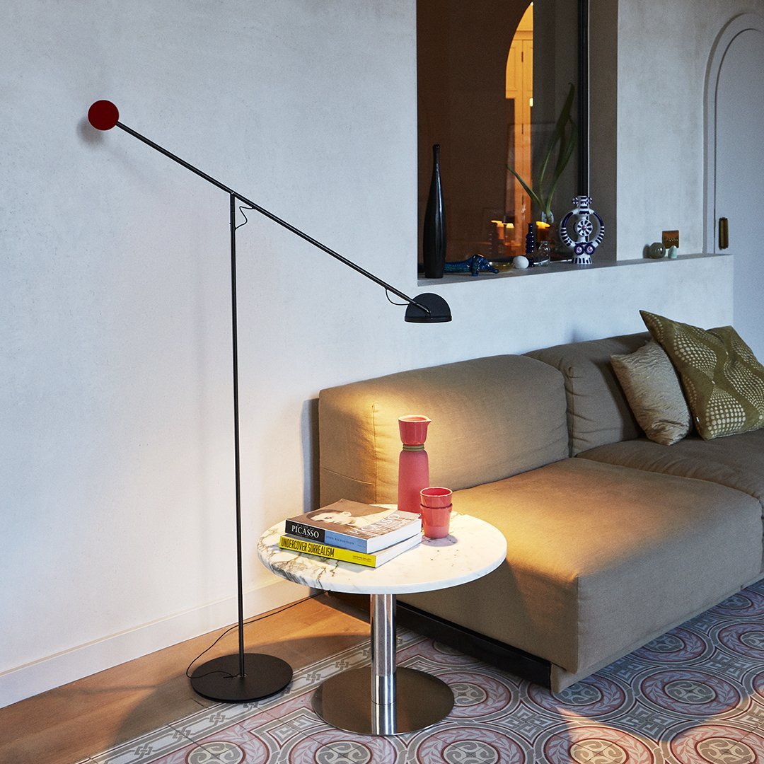 "Modern black floor lamp with a red accent, set against a neutral backdrop and colorful patterned rug."