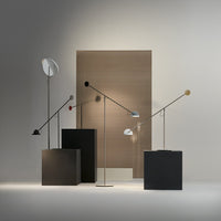 Modern floor lamps with sleek metallic finishes and geometric black and white bases against a warm neutral backdrop.