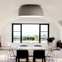 Modern minimalistic room featuring a gray ceiling lamp, white walls, and a wooden table with black chairs.