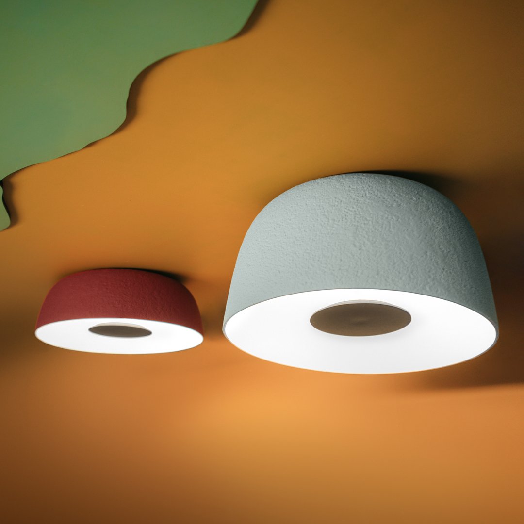 Two modern ceiling lights in red and light blue against an orange and green background, showcasing sleek, minimalist design.