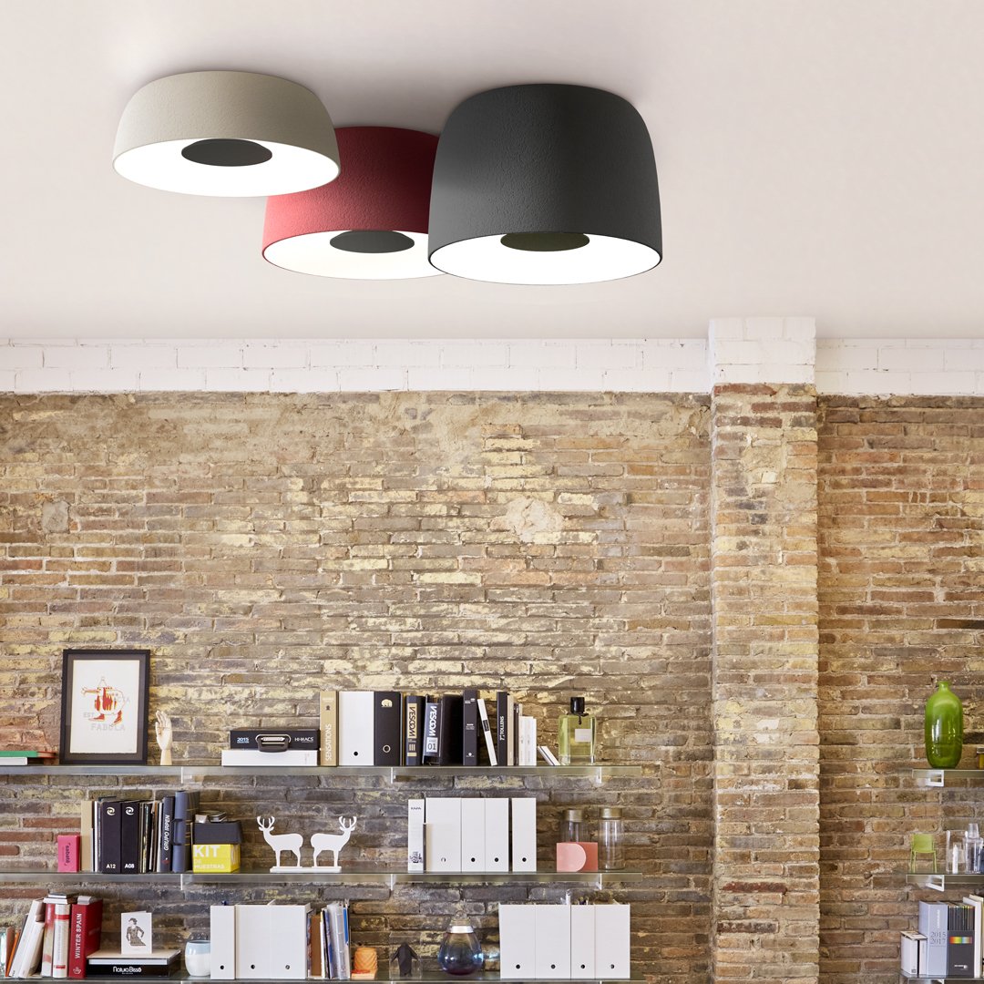 Ceiling lamp with three shades: white, red, and dark gray on a textured brick wall background. Modern and stylish design.