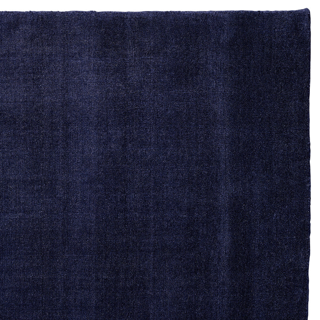 Navy blue textured rug with subtle variations in color and a soft, plush finish. Perfect for stylish interiors.