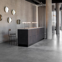 "Sleek black cabinetry with a minimalist finish, paired with round silver mirrors and a gray concrete floor."