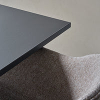 Dark gray tabletop with a smooth finish, complemented by a textured beige fabric chair.
