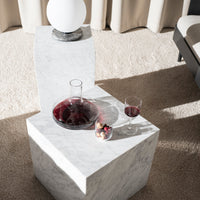 Elegant white marble table with subtle gray veining, featuring glassware in rich red and colorful decor accents.