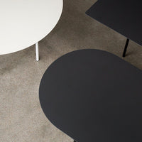 Modern round tables in sleek white and deep black against a textured gray surface. Minimalist design, perfect for contemporary decor.