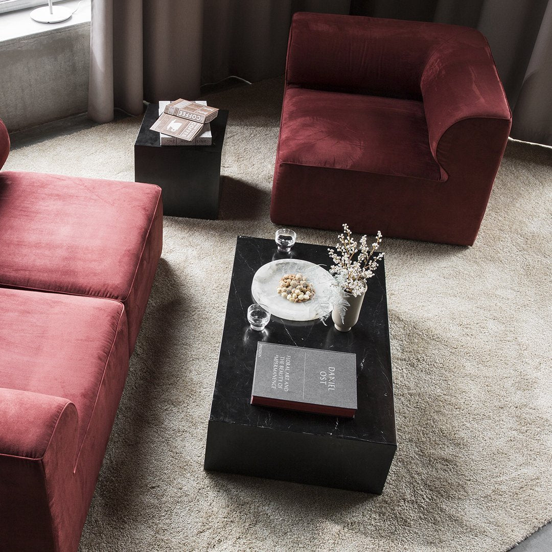"Plush burgundy sofas paired with a sleek black coffee table on a soft beige carpet, accented with neutral decor."