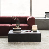Modern black coffee table with a minimalist design, surrounded by a burgundy sofa and neutral-toned decor.