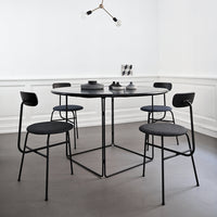 Modern black dining table and chairs with gray upholstery against a minimalist white backdrop. Geometric decor accents in gray.