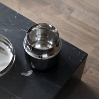Silver and black sleek container with polished metal accents, set on a matte black surface.