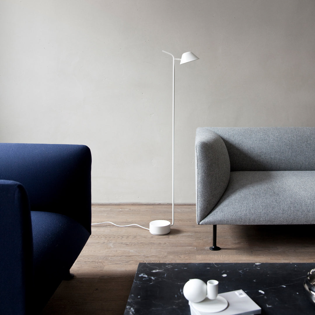 Minimalist living room featuring a blue sofa, gray couch, and sleek white floor lamp against a neutral wall.