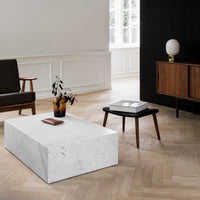 White marble coffee table with subtle gray veining, surrounded by warm wood tones and minimalist decor.