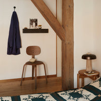 "Warm wood tones, deep purple fabric, and a geometric quilt with teal and cream patterns create a cozy atmosphere."
