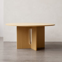 Round wooden dining table in light natural wood finish with a sleek, minimalistic design.
